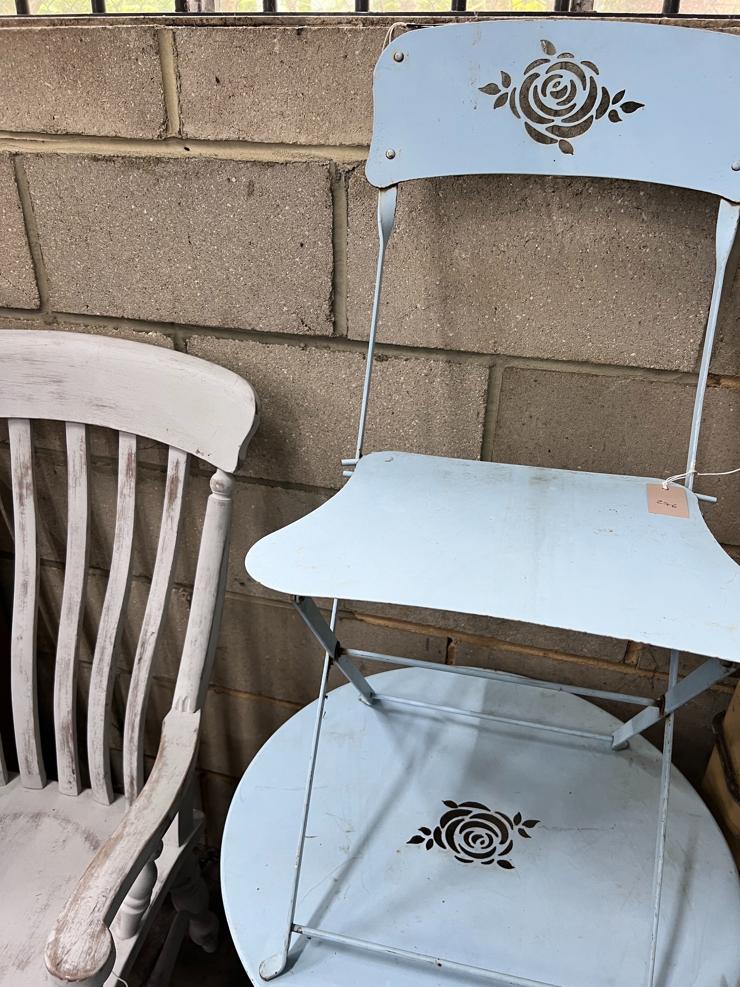 A blue painted wrought iron folding cafe table and pair of matching chairs, diameter 60cm, height 69cm *Please note the sale commences at 9am.